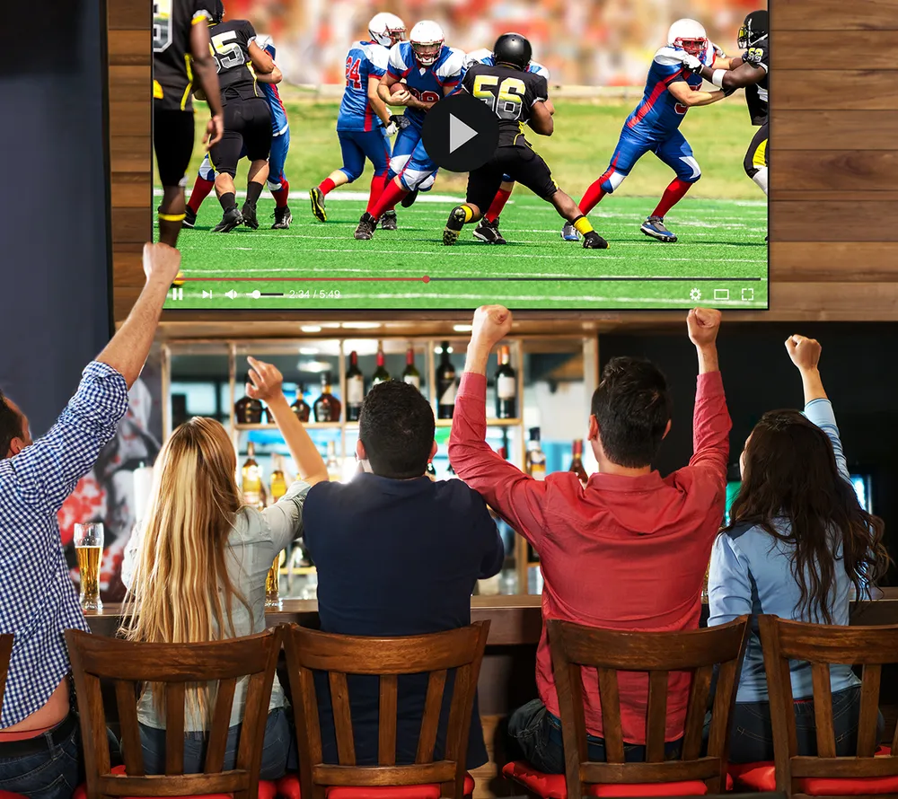a crowd of people cheering while watching football at a sports bar