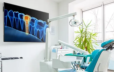 Dentist chair in a check up room with a large screen on the wall showing dental work