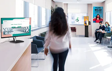 Woman walking past a check in station in a hospital waiting room