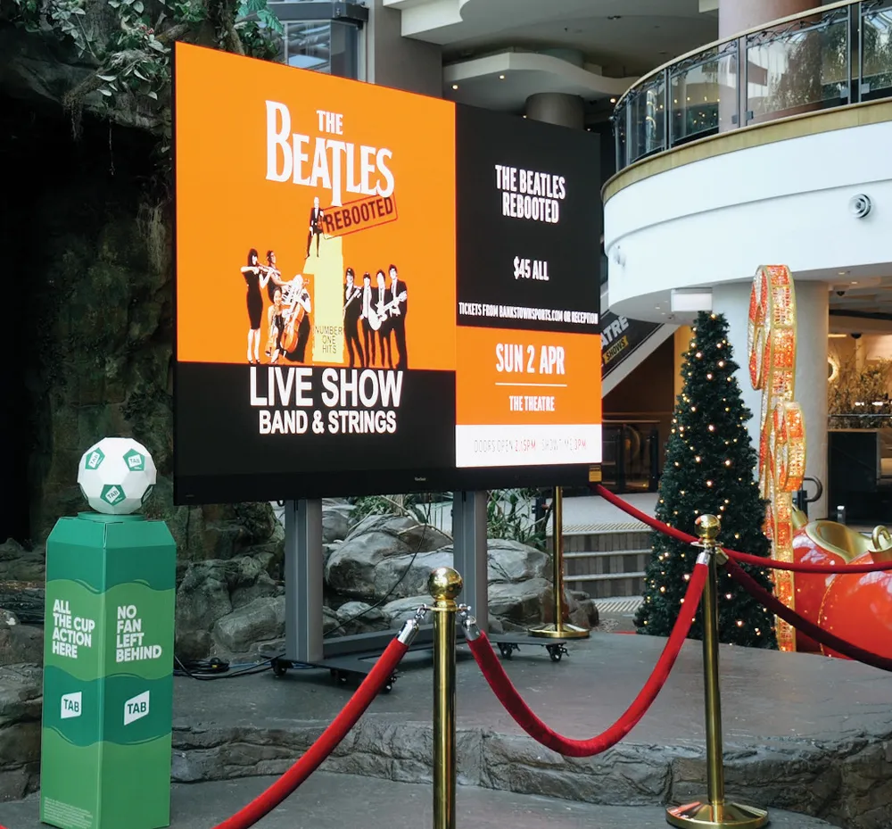 an advertisement for a concert shown on a large display in a shopping area