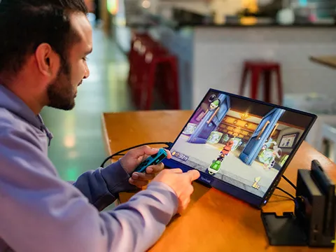 Man using his portable monitor to play a video game