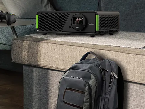 a projector next to a backpack and video game controller