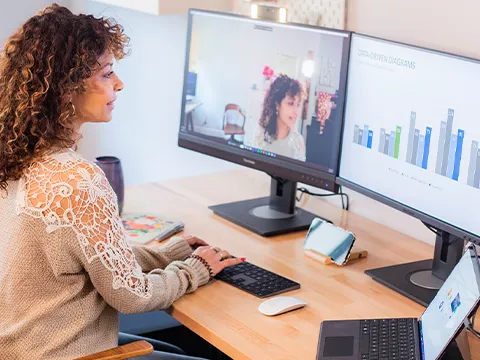 someone using dual monitors for a video call and a presentation at once