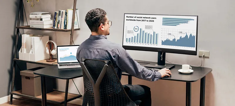 a man looking at charts on an ultrawide monitor