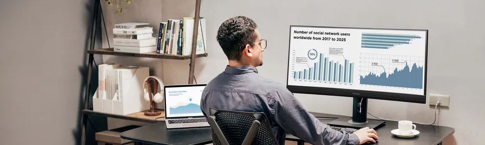 a man looking at charts on an ultrawide monitor