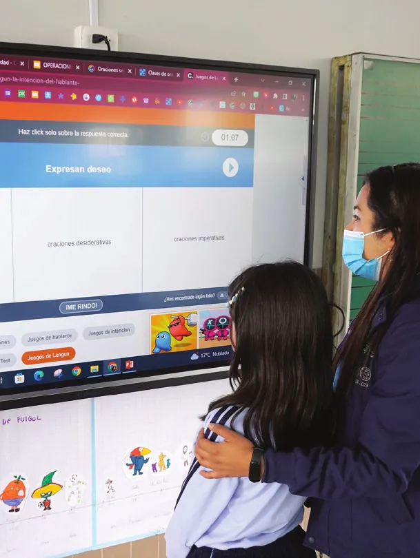 a masked teacher with her arm around a student both looking at a lesson on a ViewBoard display