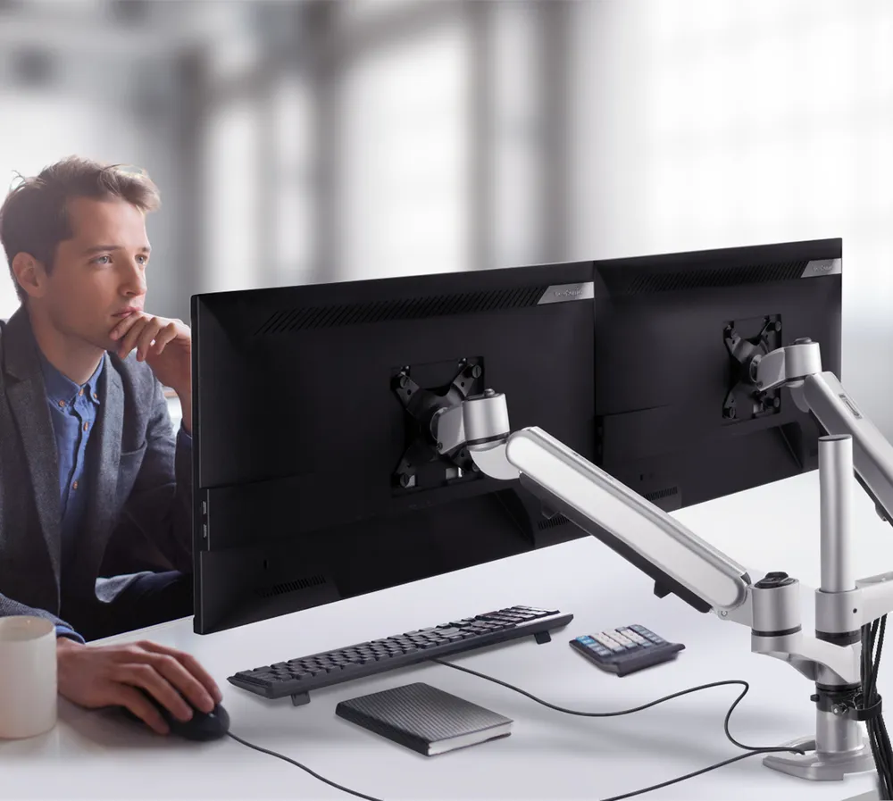 man working at desk with dual monitors using mounting arms