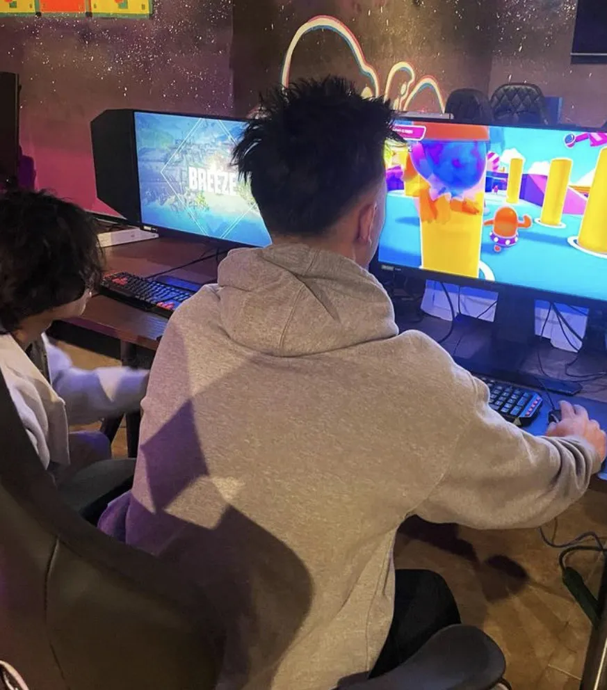 two gamers at computers sitting next to each other