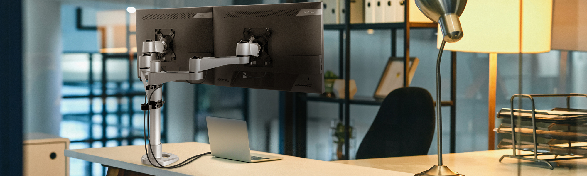 a desk with two monitors mounted to a dual mounting arm